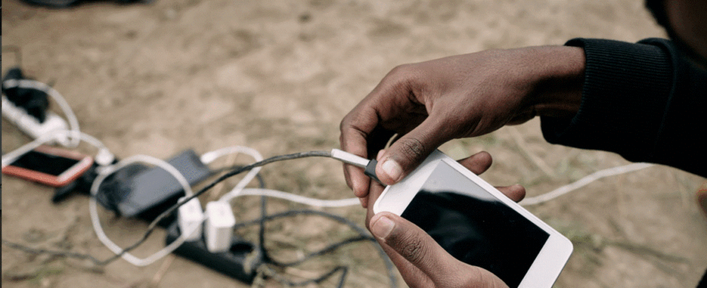 Tourist using solar station to charge devices at remote safari camp lodge.
